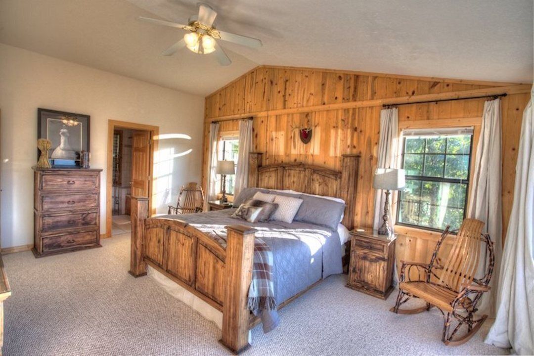 Un dormitorio rústico con una cama de madera, cómoda y mecedora.