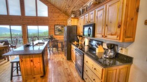 A spacious kitchen with wooden cabinets, a large island, and a view of the mountains.