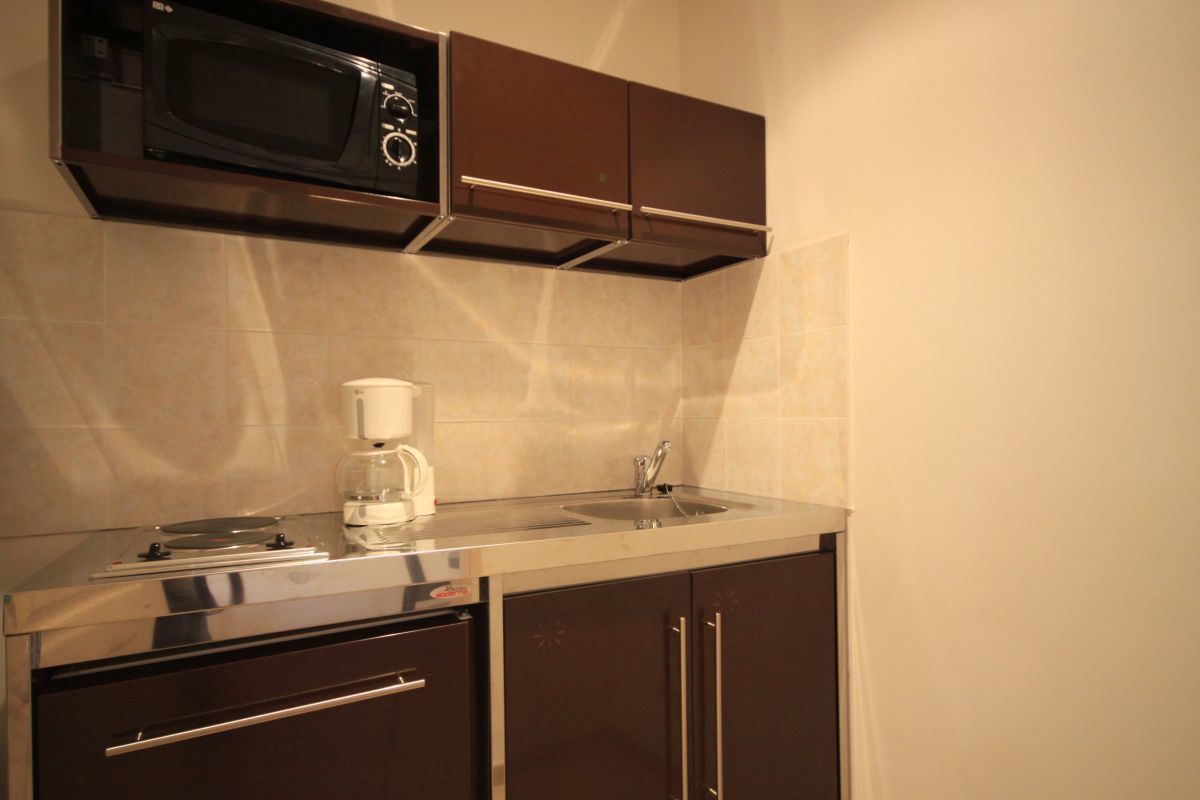 A compact kitchen with a microwave, coffee maker, and sink.