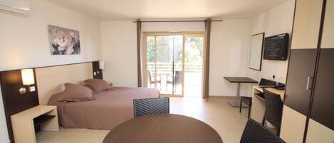 Quarto de hotel moderno com cama, mesa de jantar, escrivaninha e televisão.