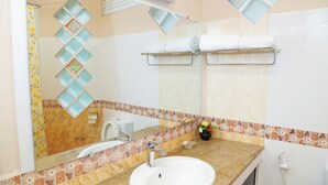 A bathroom with a sink, mirror, towel racks, and a shower.
