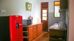 A compact kitchen with wooden cabinets, a red refrigerator, a microwave, and a coffee maker.