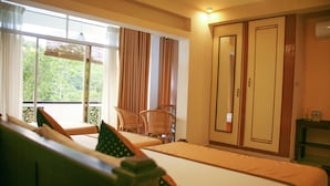 A hotel room with two beds, a window with curtains, a chair, and a wardrobe.