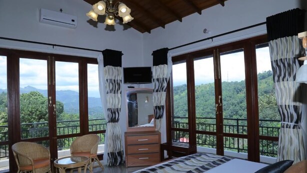 A bedroom with a bed, a dresser, a television, and two wicker chairs.