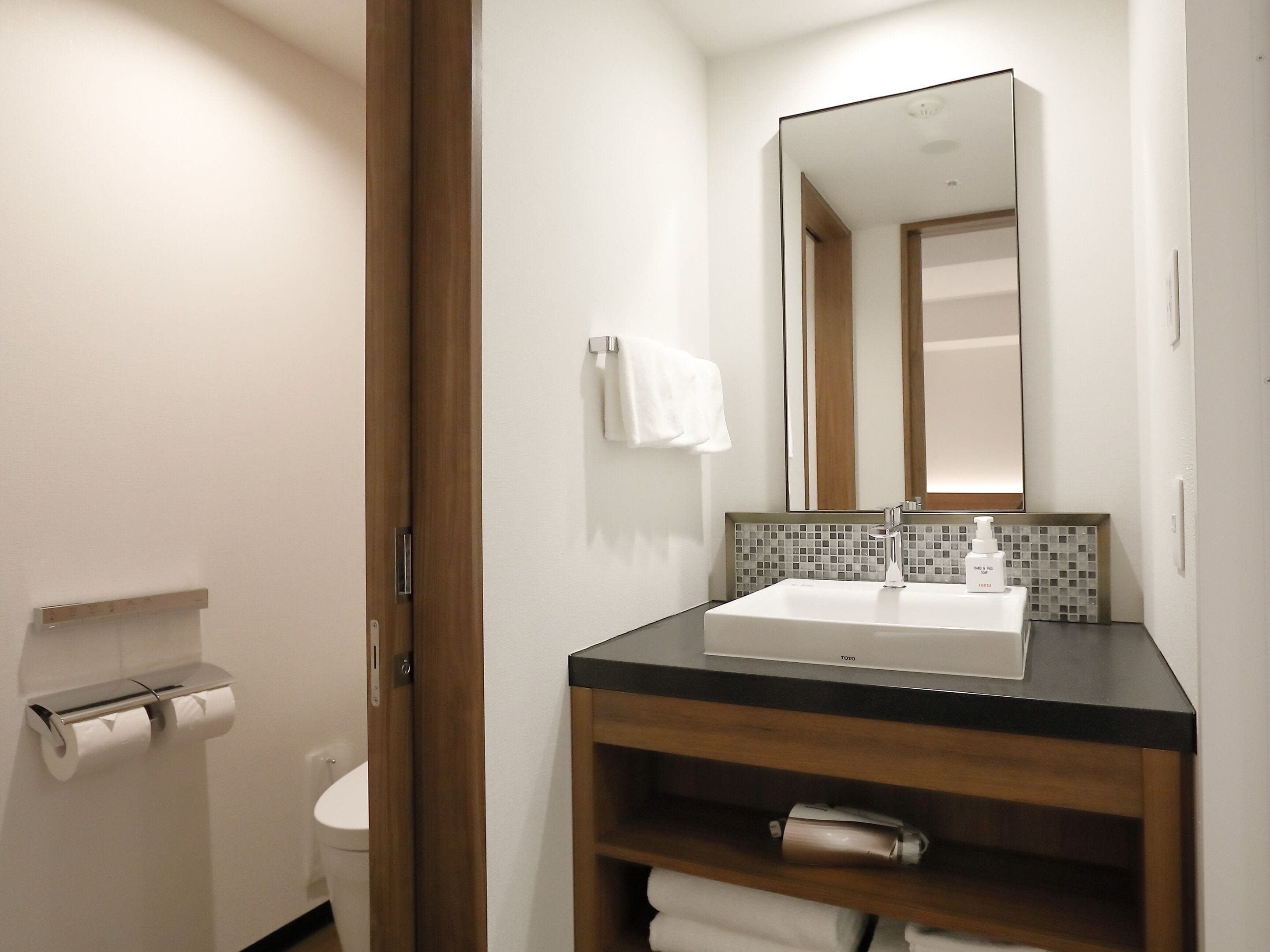 A modern bathroom with a white sink, a mirror, and a towel rack.