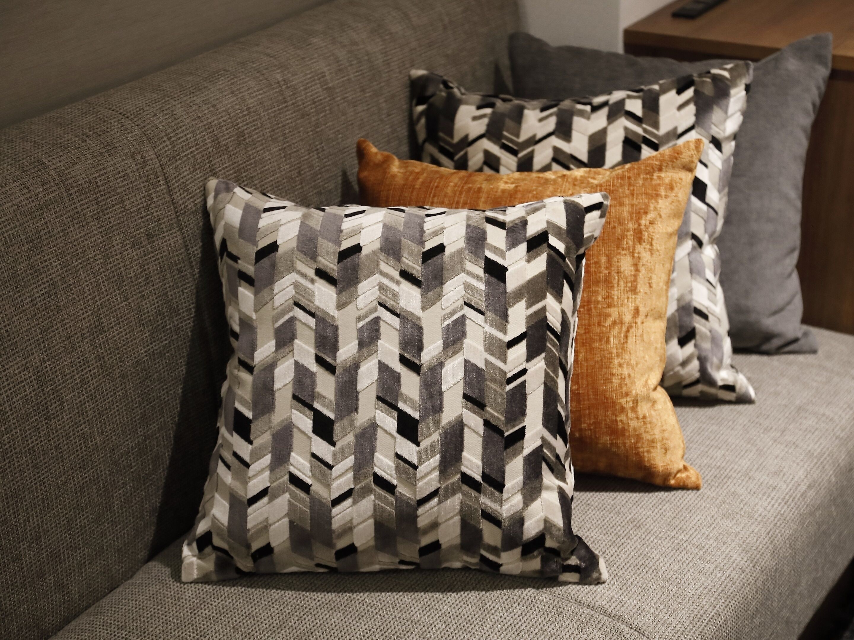 A sofa with three pillows in different patterns.