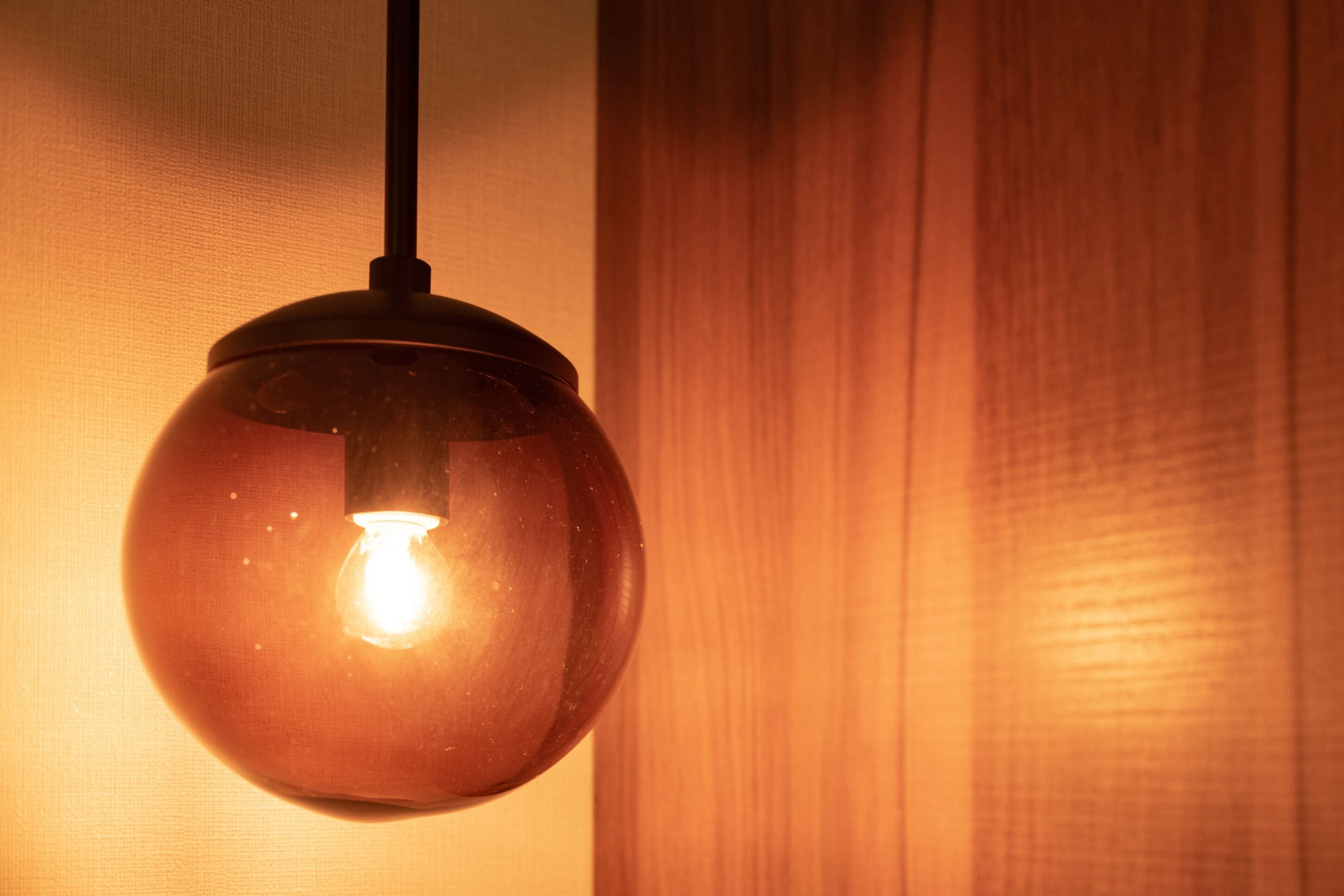 A spherical pendant light fixture with a visible filament bulb, hanging from a black cord.