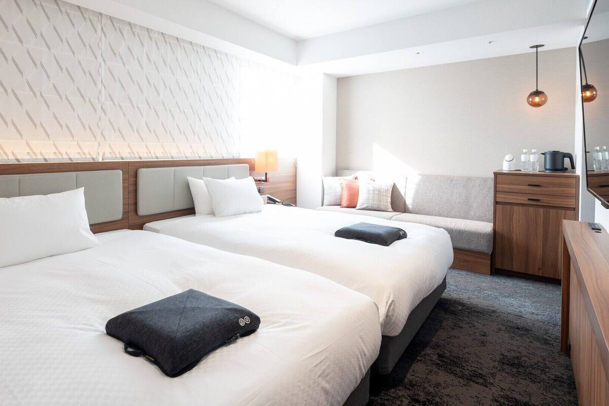 Ein Hotelzimmer mit zwei Betten, einer Sitzecke, einem Schreibtisch und einem Kleiderschrank.