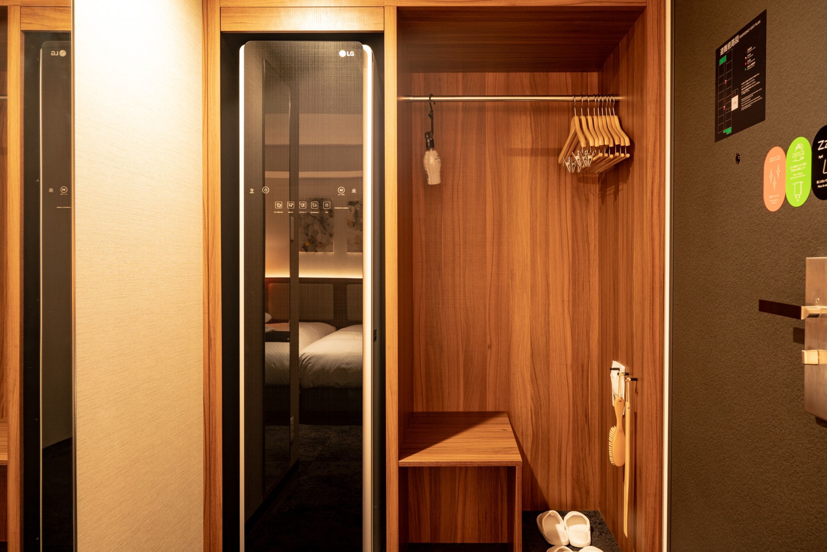 A hotel room with a wooden interior, a bed, a small table, a shoe rack, and a wall-mounted phone.