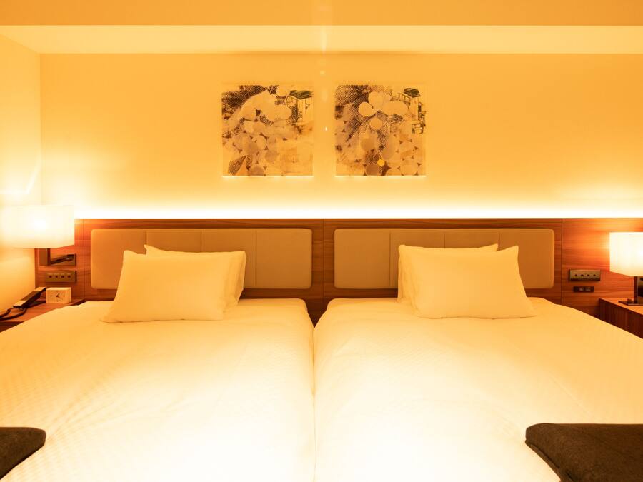 A double bed with two pillows, a nightstand with a lamp, and a wall-mounted artwork.