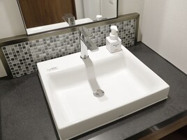 A white bathroom sink with a modern faucet and a soap dispenser.