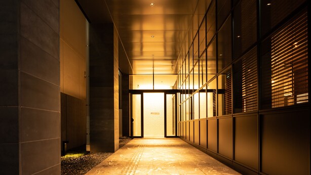A corridor with a tiled floor, a glass door at the end, and a wall with a grid pattern. - Hotel Forza Hakataeki Chikushi - Guchi II (Fukuoka)