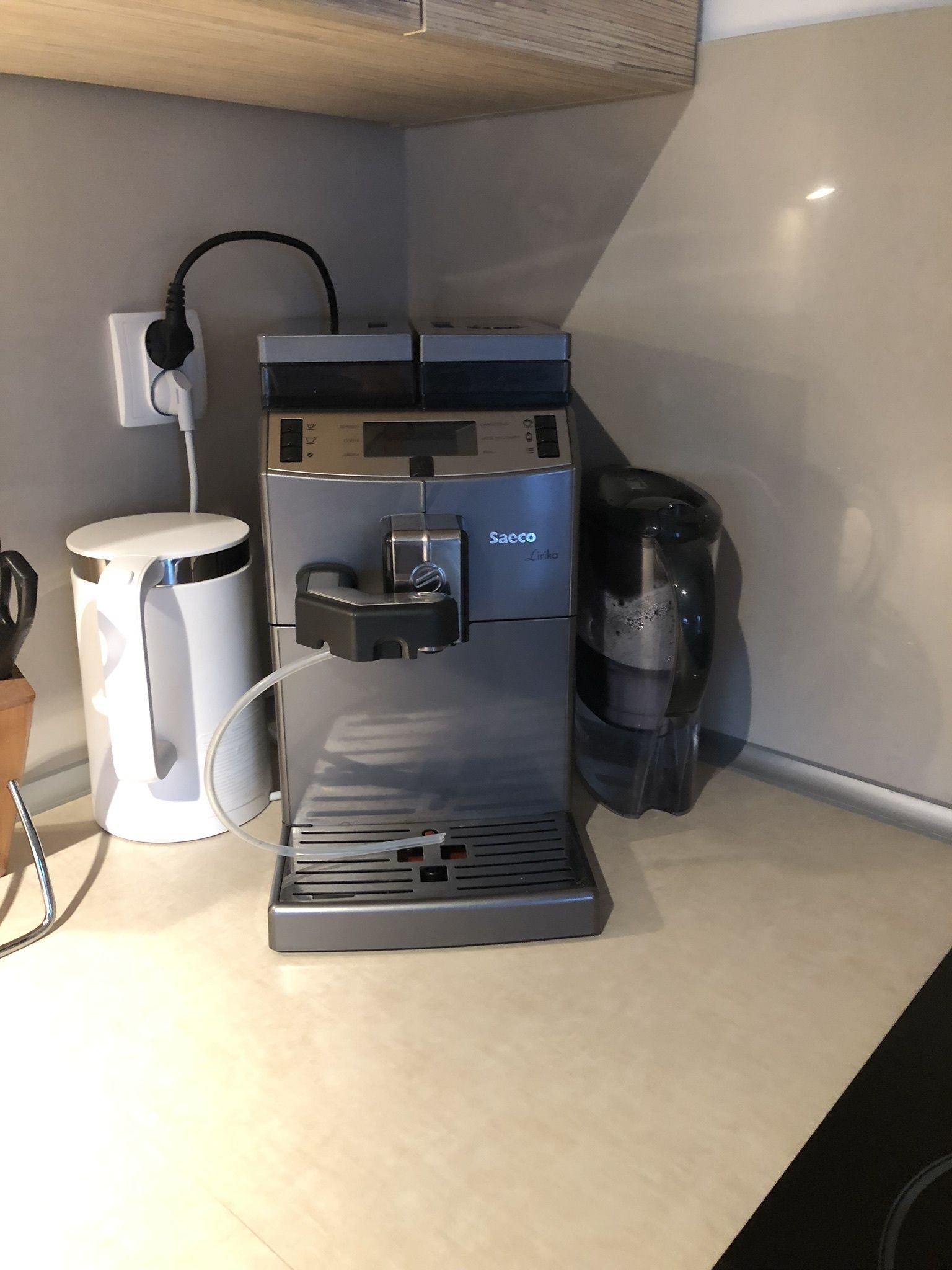 Une machine à café avec un réservoir d’eau, un compartiment pour les capsules de café et une tasse posée sur le comptoir.