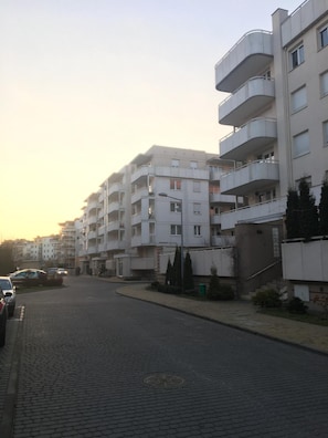 Eine Wohnstraße mit mehrstöckigen Wohngebäuden, einer gepflasterten Straße und geparkten Autos.