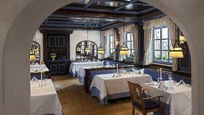 An interior with tables set for dining, a wooden floor, and a view through an arched doorway. - Maximilian Quellness- und Golfhotel (Bad Griesbach im Rottal)