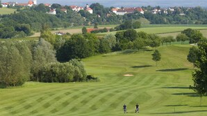 A golf course with a clear view of a town in the background, including a prominent clock tower. - Maximilian Quellness- und Golfhotel (Bad Griesbach im Rottal)