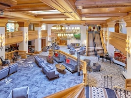 A spacious lobby with multiple seating areas, a grand staircase, and a chandelier.