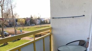 A balcony with yellow railings, a small round table, and two wicker chairs. - Apartament Przy Skarpie (Torun)