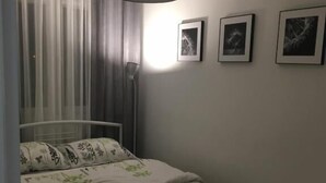 A bedroom with a bed, a hanging light fixture, and three framed pictures on the wall. - Apartament Przy Skarpie (Torun)