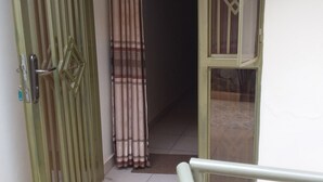 A view of a room with a door, a curtain, and a window. - Plata Guest House (Kigali)