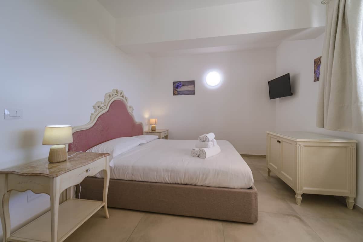 Une chambre d’hôtel avec un lit, une table de chevet, une lampe et un téléviseur fixé au mur.