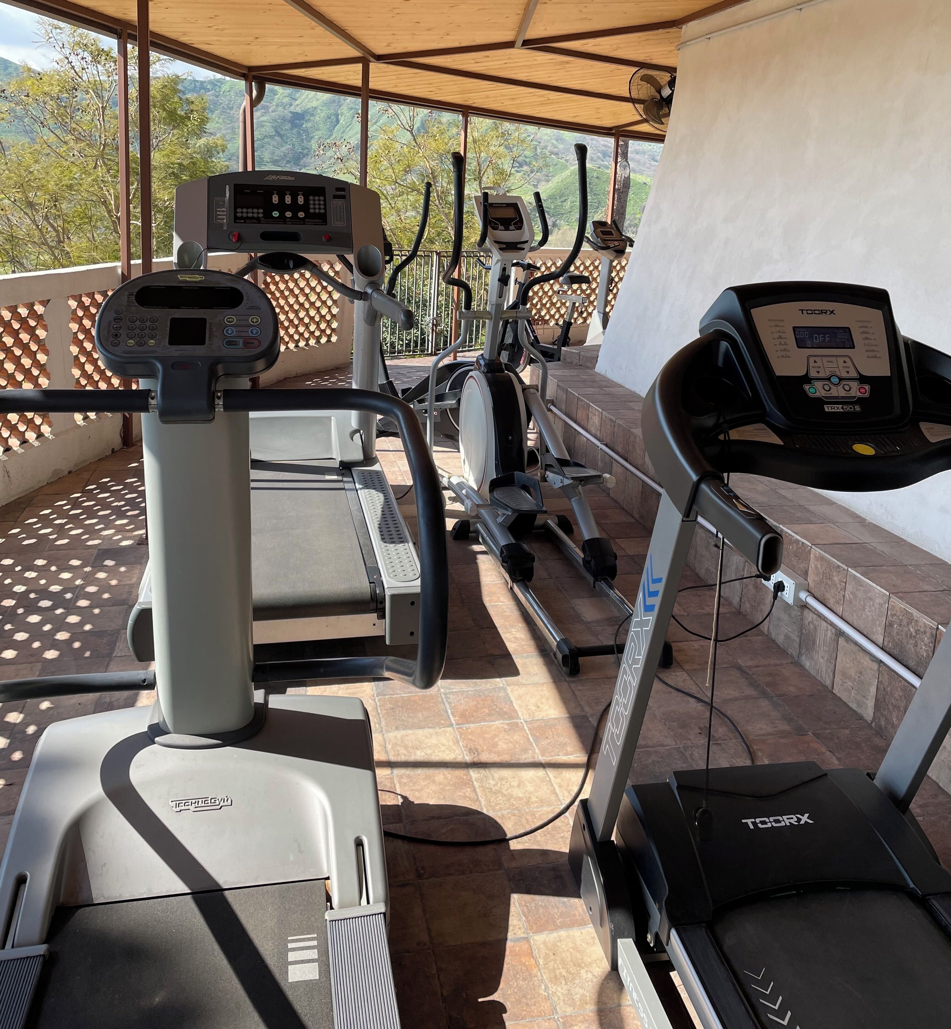 Un espace de remise en forme extérieur abrité, équipé de plusieurs vélos d’appartement et de tapis de course.