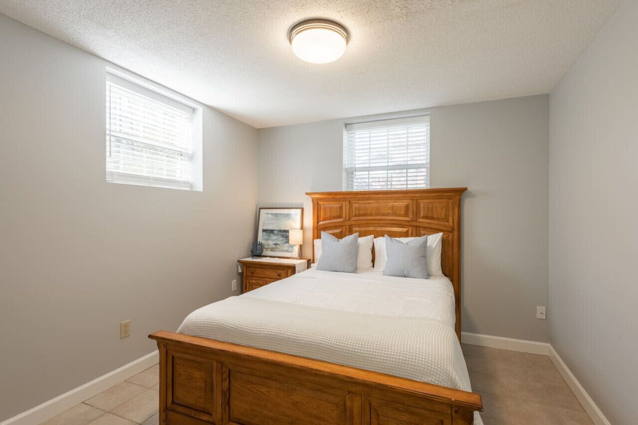 Un dormitorio con cama de madera, dos mesitas de noche y una lámpara de techo.