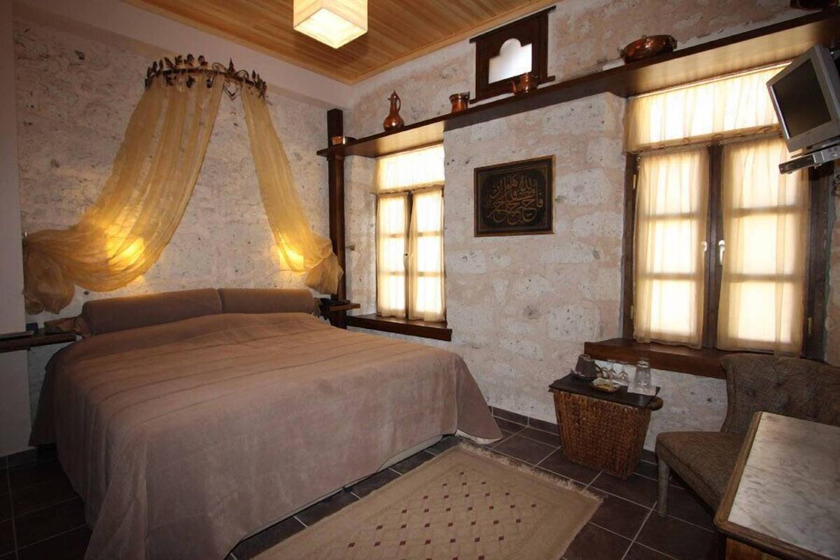 A bedroom with a large bed, a small table, a chair, and a television.