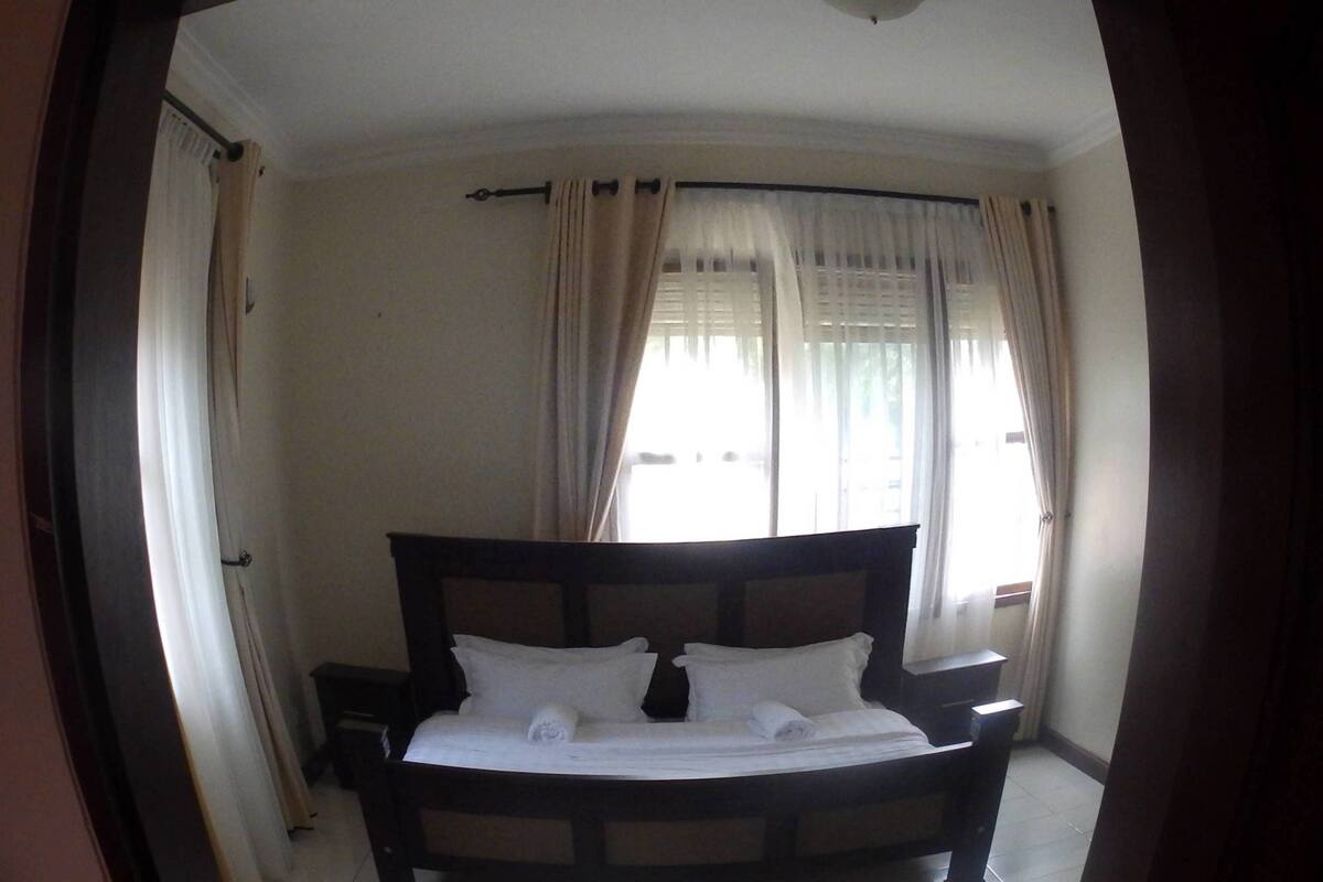 A bedroom with a bed, curtains, and a ceiling light.