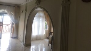 Un pasillo con suelo de baldosas, un arco de entrada y una silla.