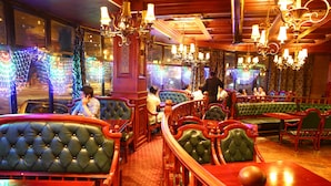 A restaurant interior with booths, wooden tables, and hanging chandeliers. - Royal house hotel (Ulaanbaatar)