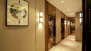 A hallway with a framed artwork, wall sconces, and a marble floor. - Royal house hotel (Ulaanbaatar)