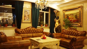A luxurious living room with leather sofas, a chandelier, and framed artwork. - Royal house hotel (Ulaanbaatar)
