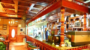 A bar area with wooden bar stools, a counter with bar equipment, and a visible exit sign. - Royal house hotel (Ulaanbaatar)