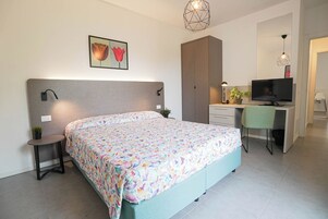 A bedroom with a bed, bedside tables, a desk, a television, and a wardrobe.