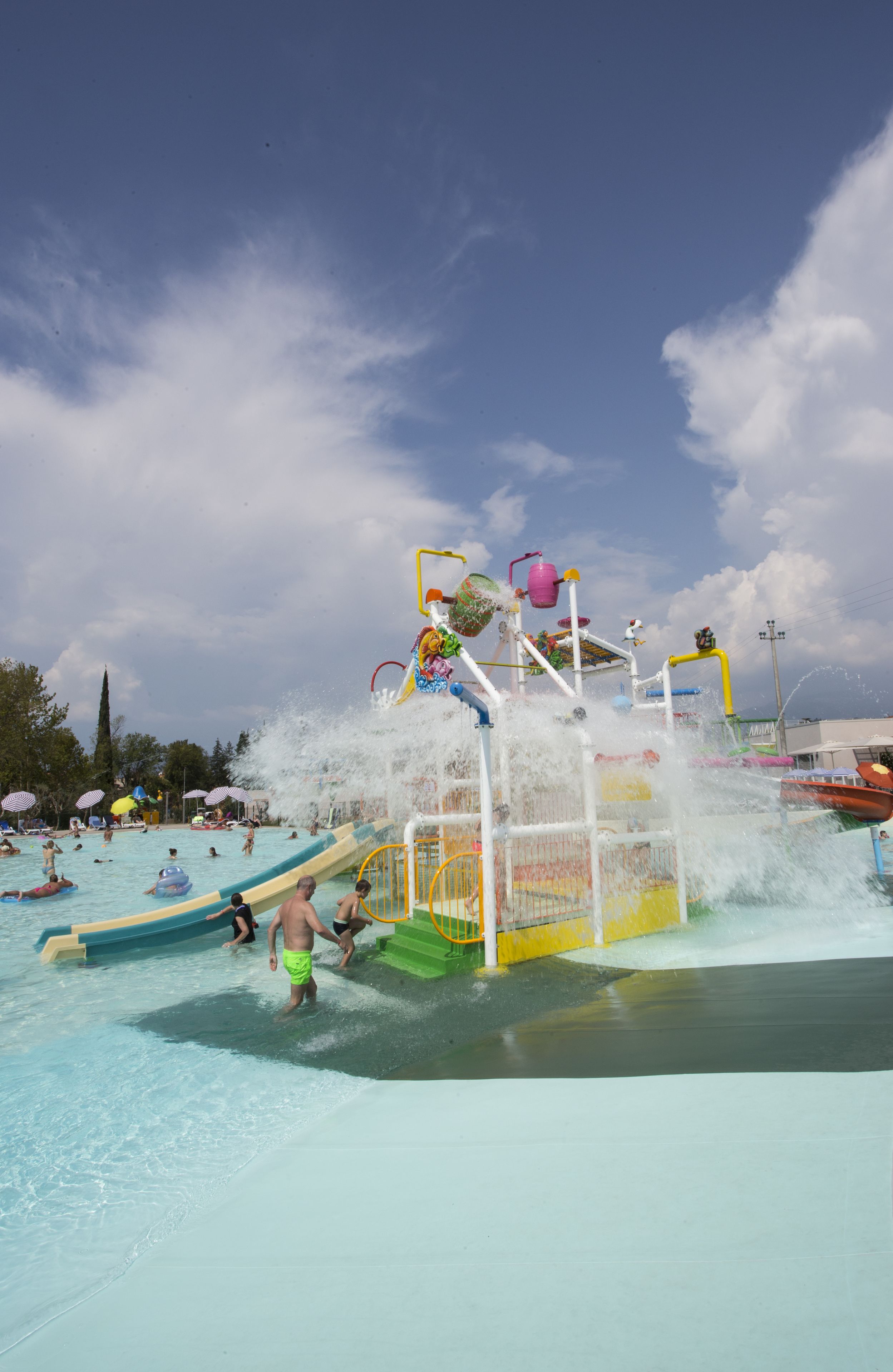 Parque acuático con tobogán de agua, piscina y diversas atracciones acuáticas.