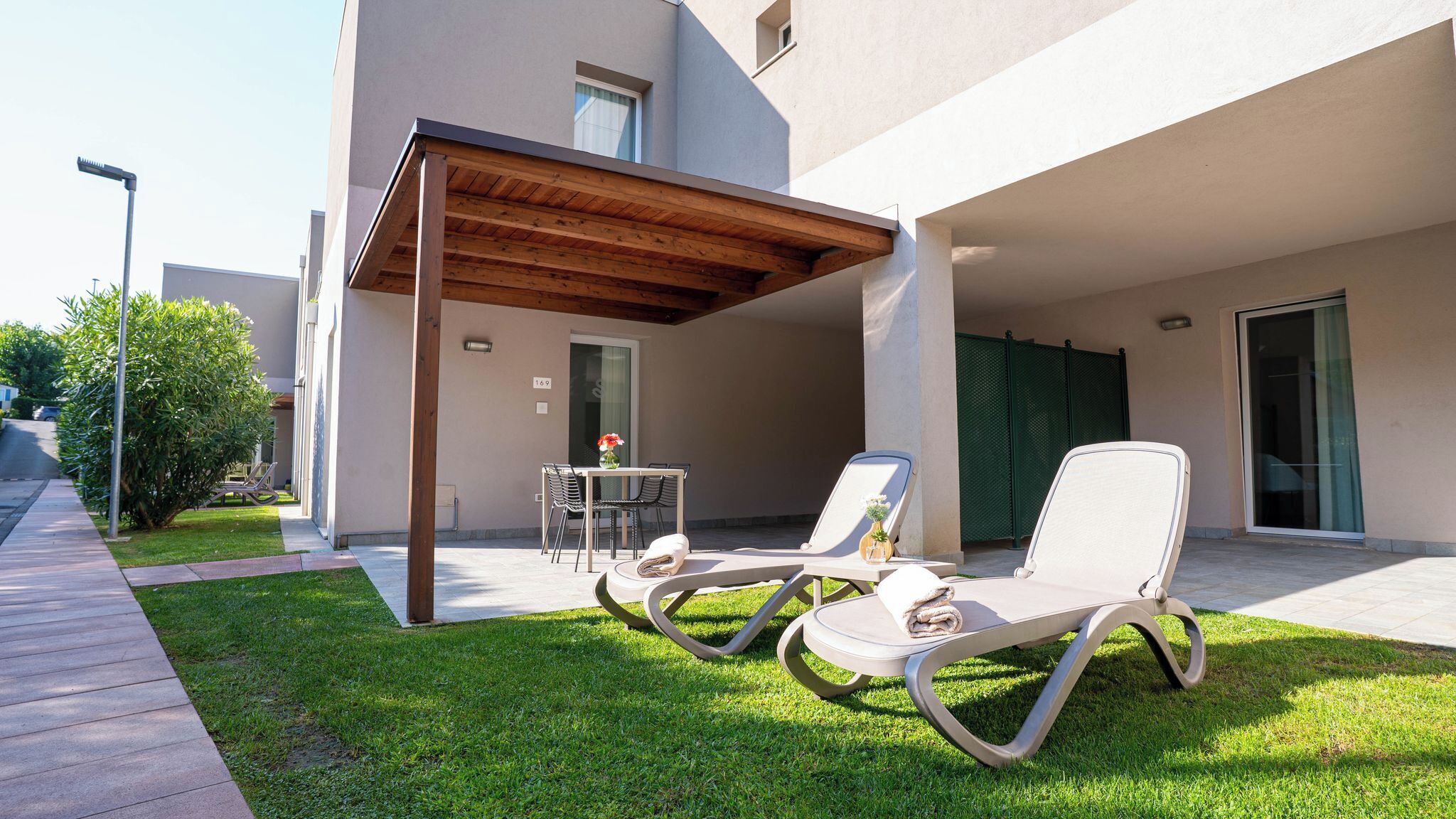Un área de estar moderna al aire libre con dos sillones, una mesita y un porche cubierto.