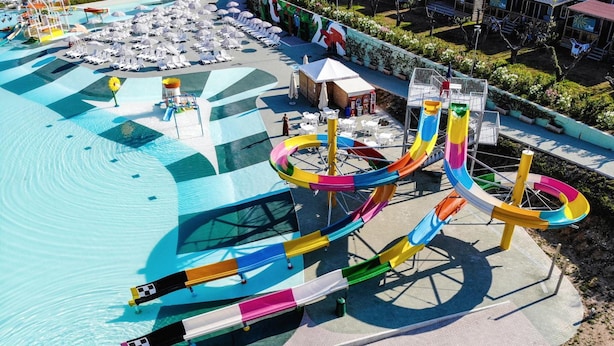 Un parco acquatico con diverse scivolate e area piscina con lettini e ombrelloni.