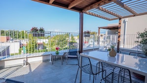 Un balcone con vista sulla città, un tavolo con sedie e un vaso con fiori.