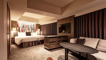 A hotel room with a bed, a sofa, a coffee table, a TV, and a bookshelf.