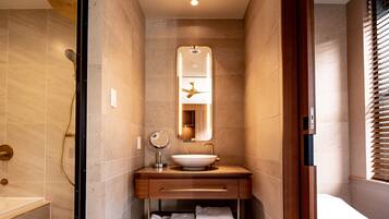 A modern bathroom with a freestanding bathtub, a vanity with a sink, a mirror, and a toilet.