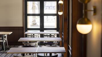 Enjoy meals in this dining area with tables and chairs, surrounded by a geometric patterned floor and natural light from the large window.