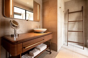 Ein modernes Badezimmer mit einem Holzkosmetikschrank, einem großen Spiegel, einem Händewaschbecken und einer Metallleiter an der Wand.
