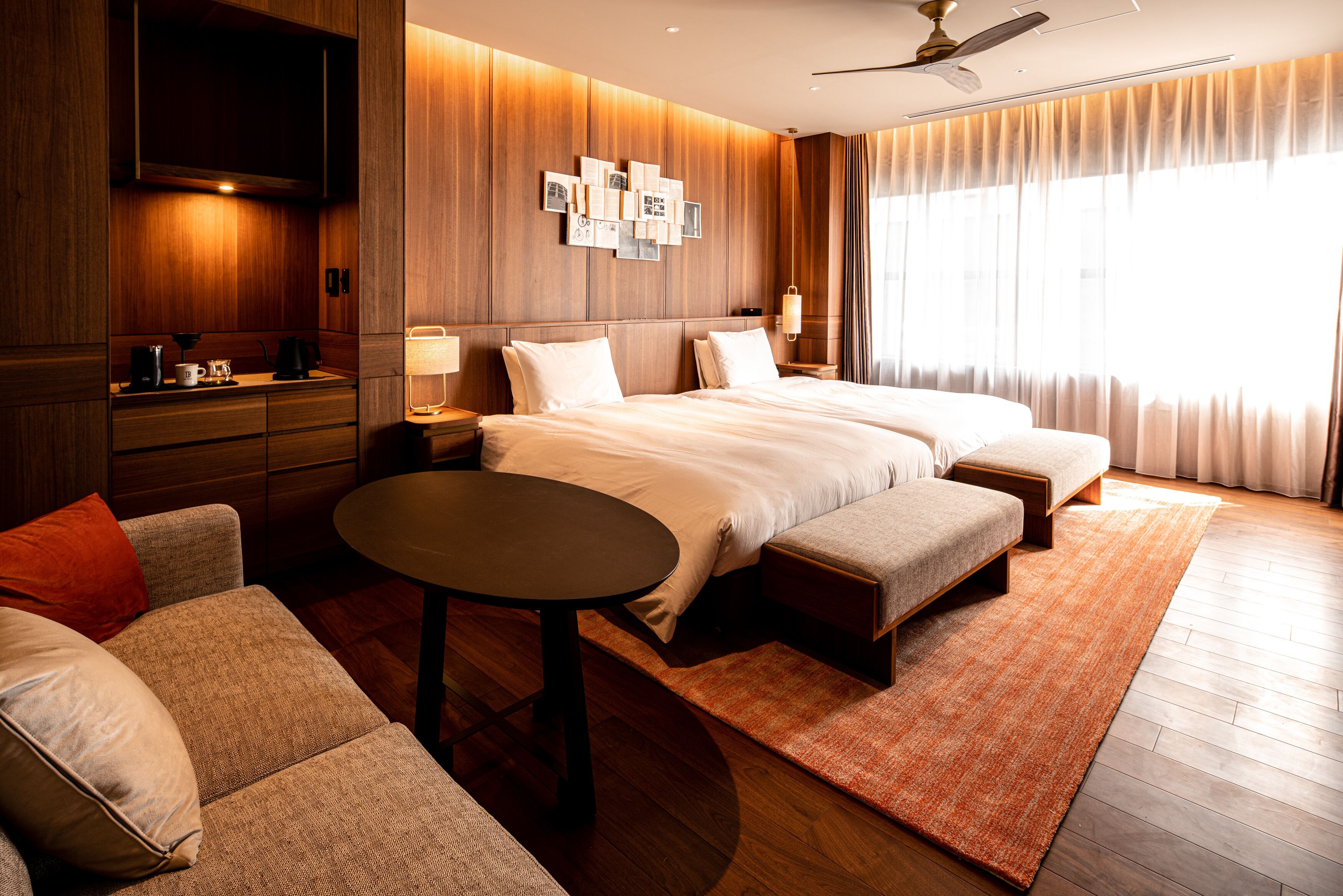 Una habitación de hotel moderna con una cama grande, un sofá, una mesita y un televisor.
