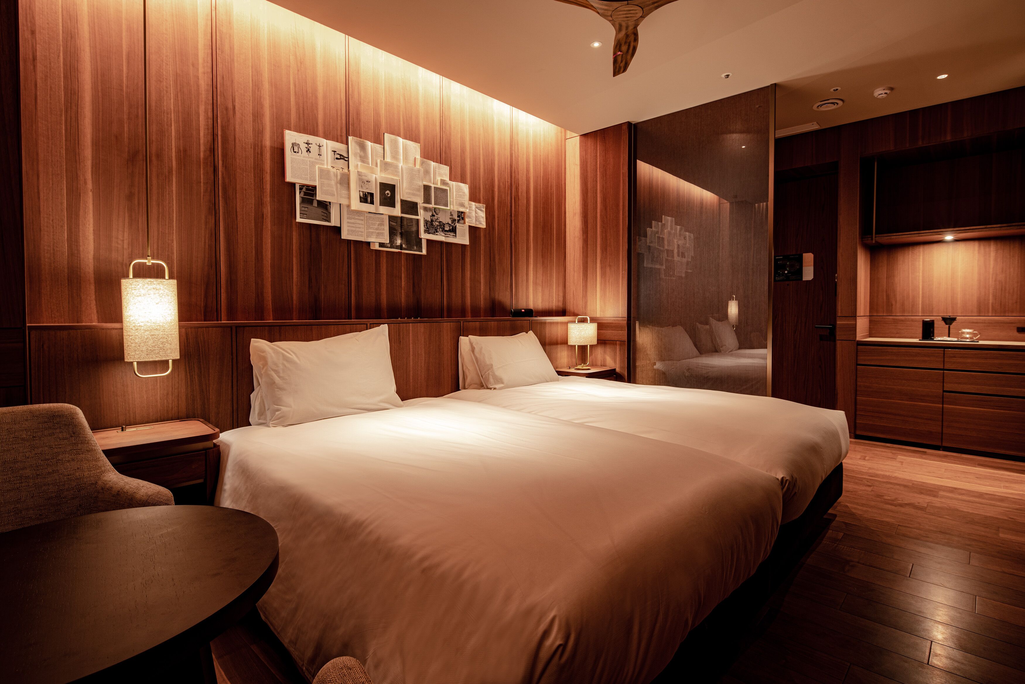 Ein Hotelzimmer mit einem großen Bett, Holzvertäfelung, einem Wandbrett, einem kleinen Tisch und einem Nachttisch mit Lampe.