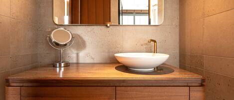 A modern bathroom with a wooden vanity, a round mirror, and a vessel sink.