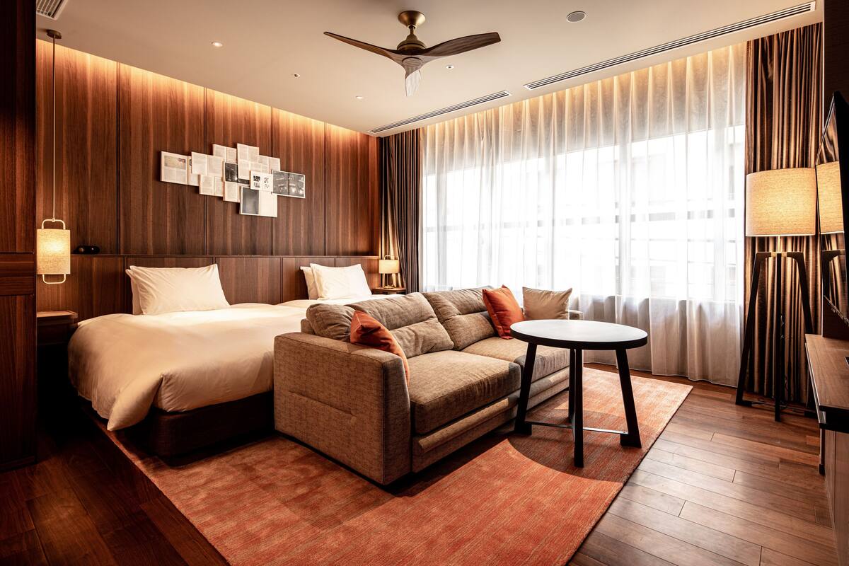 A modern hotel room with a bed, sofa, and a small table.