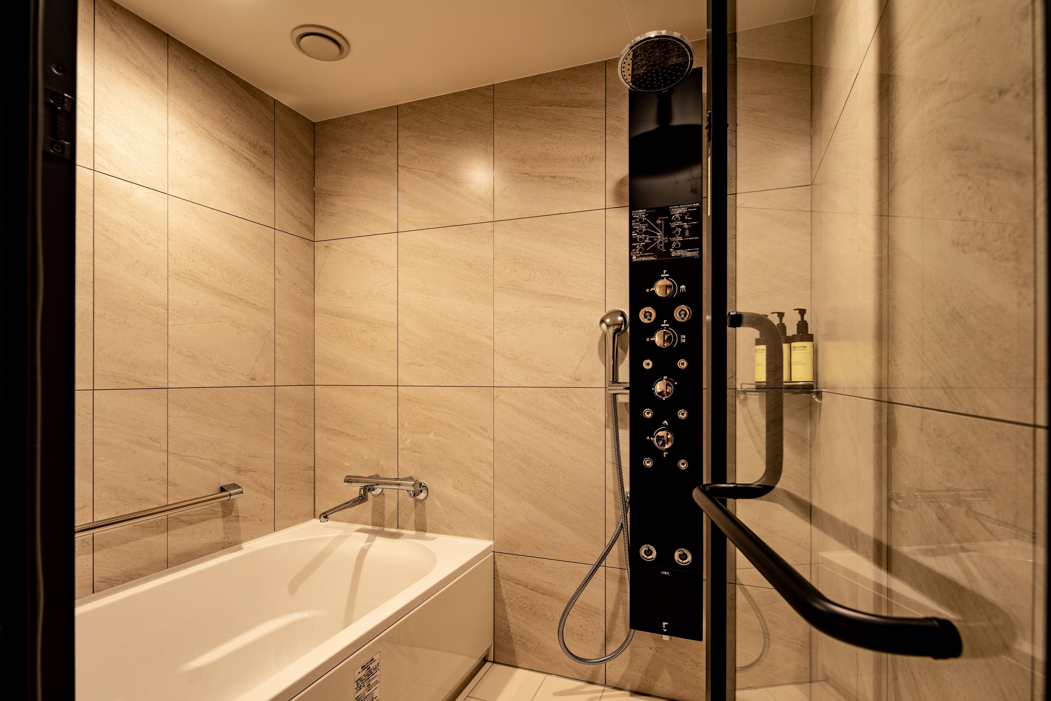 A modern bathroom with a bathtub, a shower with multiple controls, and a handrail.