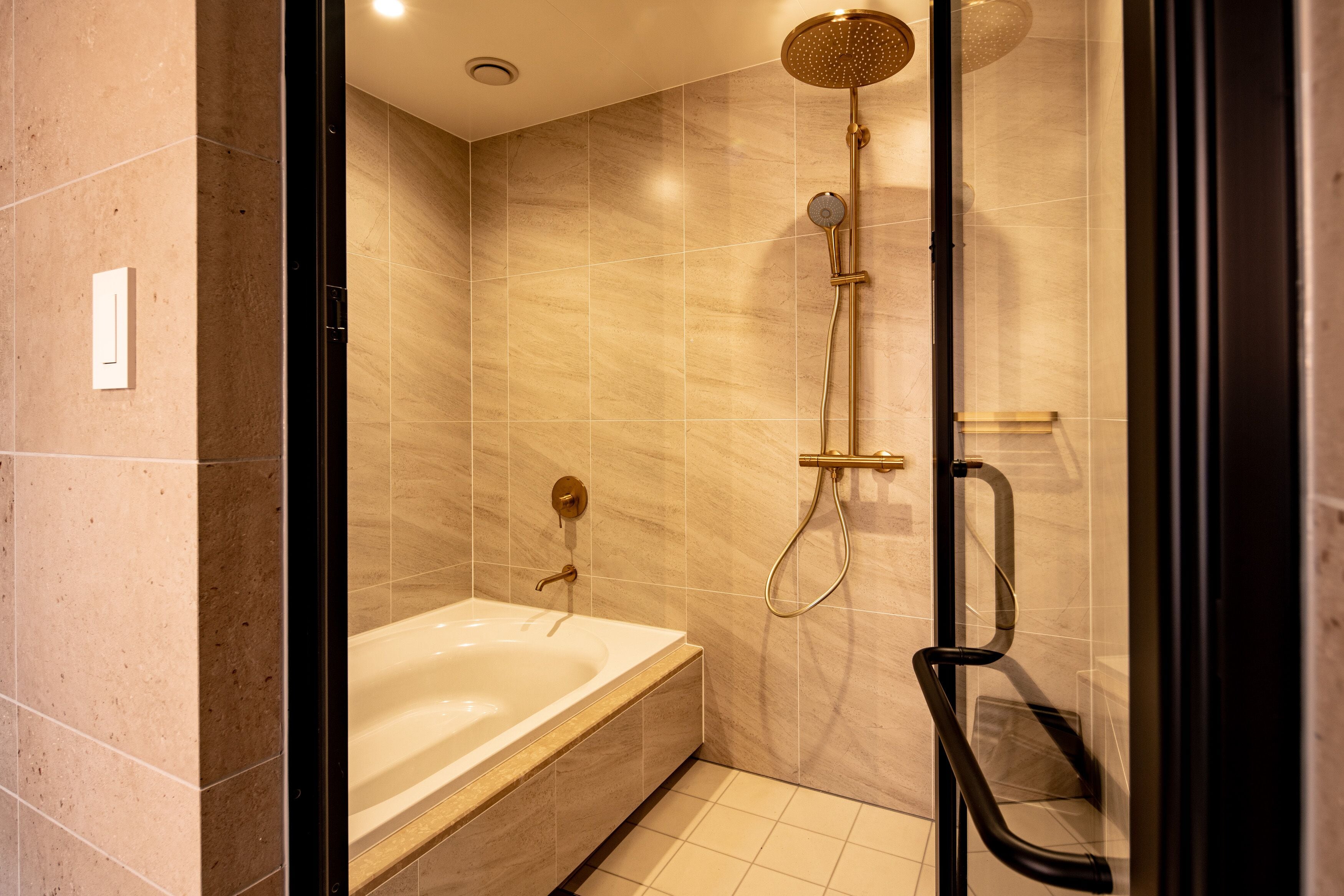 Un baño moderno con bañera, ducha con rociador de lluvia y cabina de ducha con paredes de vidrio.