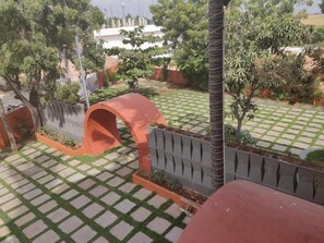 Un patio con un diseño de cuadros de césped y piedras, rodeado por un muro bajo y diversas plantas.